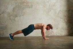 A young man doing a tuck jump from a push-up position