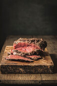 Juicy fresh cooked roast beef on rough cutting board on table