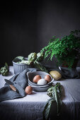 Eggs and different herbs in bowls placed on rustic table