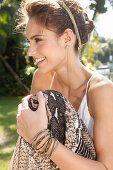 A young woman wearing hair jewellery and a white top and snake-print trousers