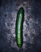 A cucumber on a grey metal surface