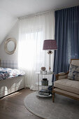 Klassischer Polsterstuhl vor blauem Vorhang im Schlafzimmer