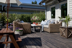 Picknicktisch und Korbsofas auf der sonnigen Terrasse am Haus