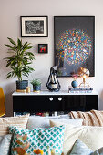 Colourful ornaments, houseplants and pictures on and over sideboard