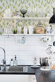 Crockery on kitchen shelves against floral wallpaper