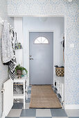 Coat rack and grey door in bright foyer