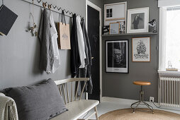 Row of pegs above spoke-back bench in grey bedroom