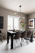 Brown leather chairs at black dining table in front of beige wall