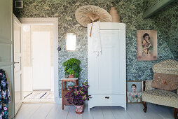 Oriental parasol on cupboard in bedroom with vintage-style wallpaper