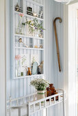 Vintage-style ornaments on narrow shelves mounted on pale blue board wall in hallway