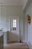 Panelled door with lattice window in pale green wall with stucco details