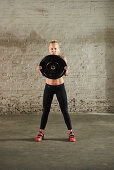 A young woman holding a weight plate at chest height