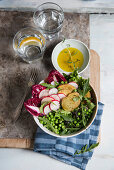 Veggie bowl with radishes, baked potatoes, peas, arugula, lettuce, radicchio and olive oil