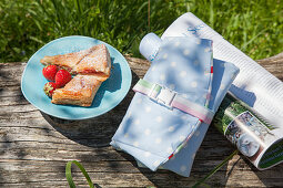 Pastries and strawberries on plate, hand-sewn picnic bag and magazine