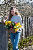 Woman carries basket of primroses and rosemary