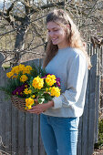 Woman carries basket of primroses and rosemary