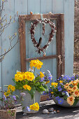 Pots of primroses and ray anemones in front of window sash with heart made of pussy willow