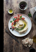 Delicious pesto hummus decorated with cherry tomatoes and beans with parsley