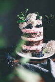 A chocolate and raspberry cake with fresh flowers and berries