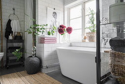 Weiße moderne Badewanne in gefliester Nische unterm Badezimmerfenster