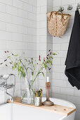 Candlestick and vase of grasses on wooden bath caddy