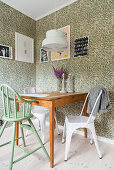 Highchair and metal chairs at kitchen table against vintage wallpaper