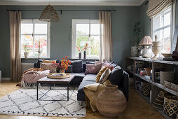 Corner sofa and ethnic accessories in interior with grey walls