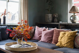 Vase of maple leaves on cork tray in living room