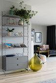 Decorative green demijohn next to modern metal shelves