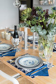 Vase of artichokes, thistles and eucalyptus on set dining table