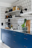 Kitchen with blue cupboards and white tiled wall