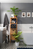 Bathroom accessories on wooden shelves between washstand and free-standing bathtub