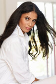 A dark-haired woman wearing a white shirt-blouse