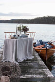 Laid table on a jetty and boat on a lake
