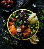 A bowl with salmon, black pasta, asparagus, pomegranate and olive cream
