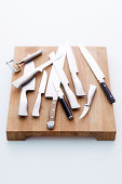 Various knives on a wooden chopping board