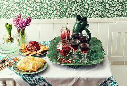 Gedeckter Tisch mit Käsekugel, Granatapfeldrinks und Blätterteiggebäck