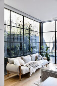 Cream-colored sofa in front of a window to the terrace and garden area