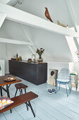 Schwarze Küchenzeile und Esstisch mit Sitzmöbeln in offenem Wohnraum unterm Dach