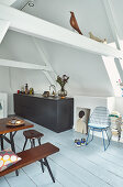 Black kitchen counter, dining table and seating in open-plan attic interior