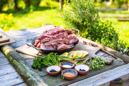 Raw spare ribs, herbs and spices on a garden table