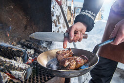 A winter barbecue: elk roulade being prepared in a pan on a barbecue (Norway)