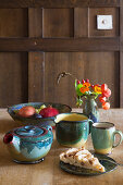 Keramikgefäße, Apfelkuchen und Herbststräusschen auf Holztisch