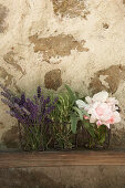 Lavendel, Salbei, Rosmarin und Rosen vor einer Steinwand