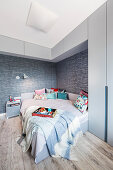 Grey bedroom with high wall-mounted cabinets above bed