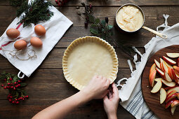 Unrecognizable woman making a apple pie on a wooden table