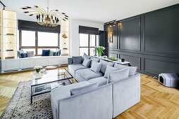 Sofagarnitur und Couchtisch aus Glas in elegantem Wohnraum mit dunkler Kassettenverkleidung