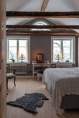 Sheepskin rug on wooden floor of bedroom with double bed and dressing table