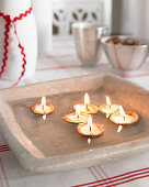 Candles in walnut shells floating in grey dish