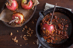 Making toffee apples with ripe red apples, dipping in toffee